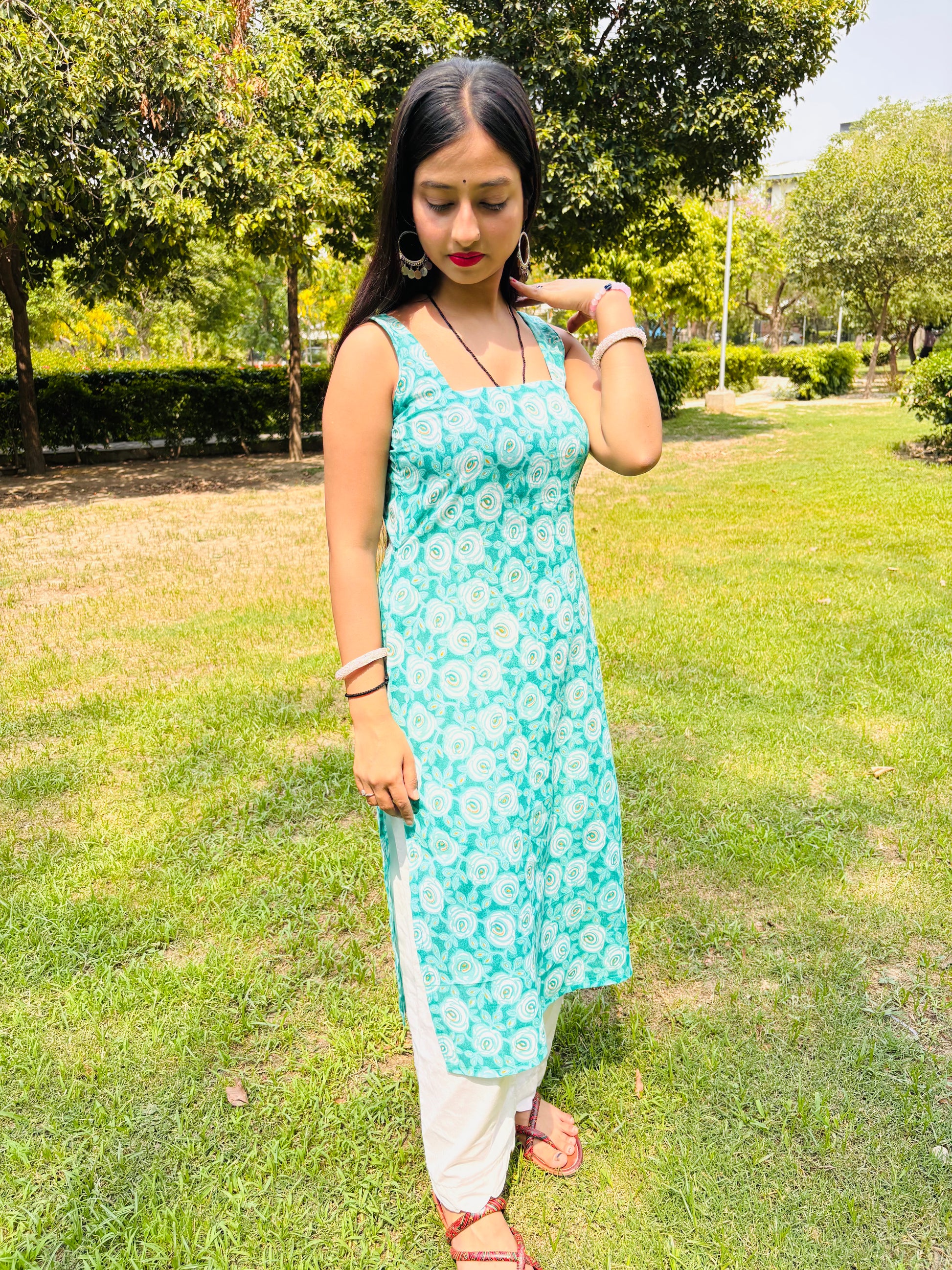 Model in Khilan Collection turquoise floral printed long cotton kurti with sleeveless design and deep back – front pose in garden