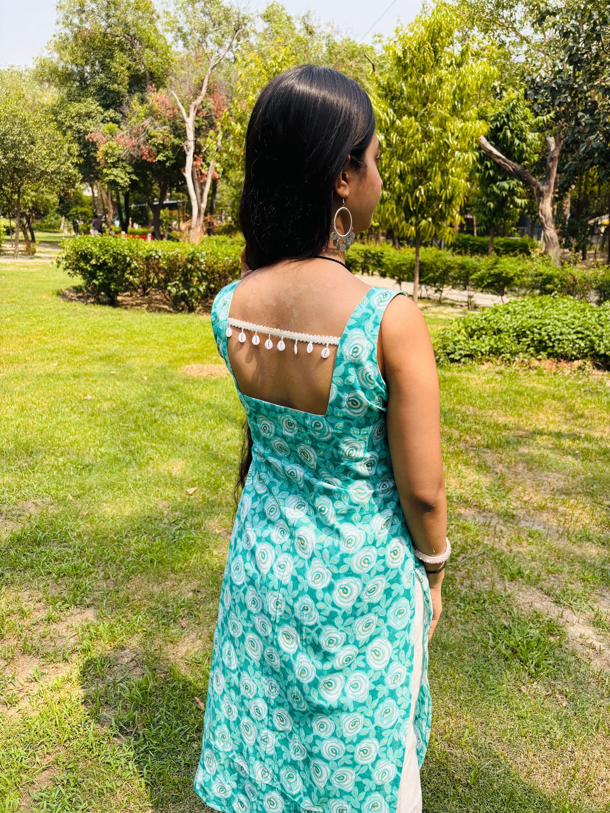 Model in Khilan Collection turquoise floral printed long cotton kurti with sleeveless design and deep back – front pose in garden